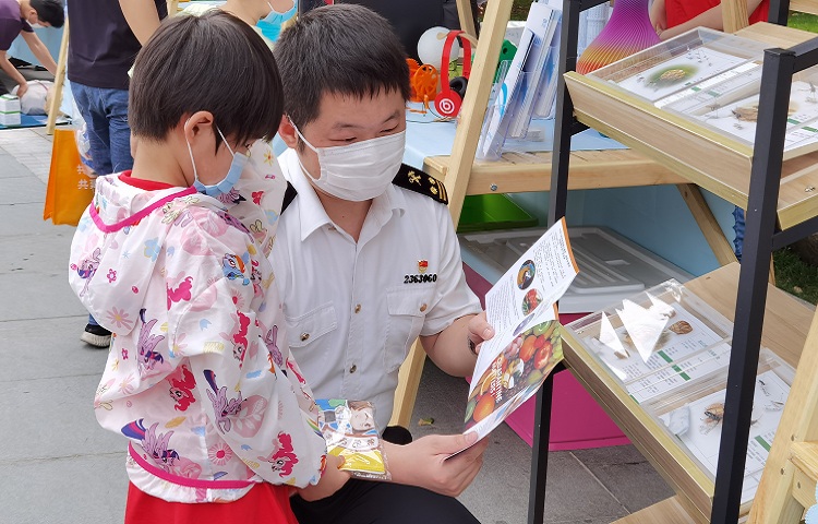 图为：海关关员为小朋友讲解宣传画册+++赵俊凌+摄