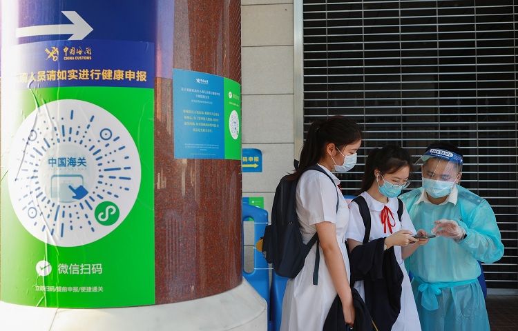 图为：海关关员在引导出境学生进行健康电子申报++俞波摄