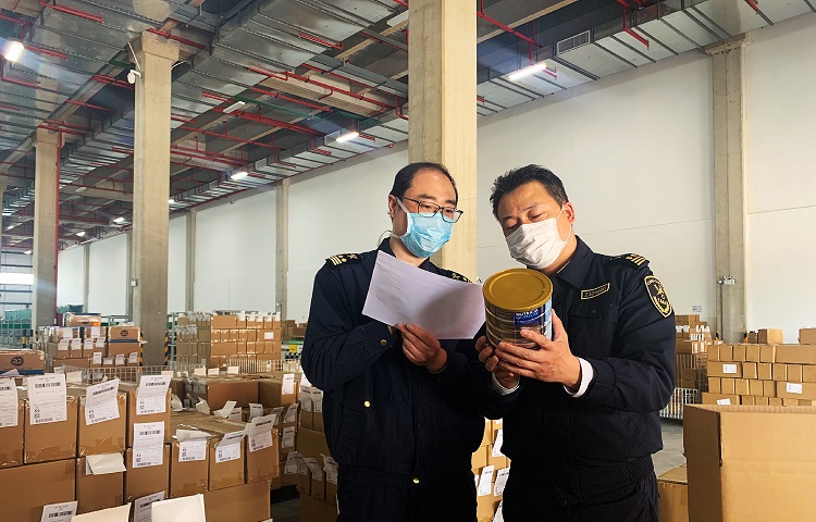 图为：金陵海关驻江北办事处关员正在对跨境保税出区货物进行清单查验+吴疆摄20200430