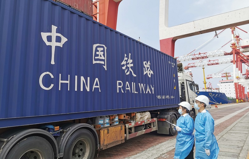 图为：回程班列集装箱在海关关员的监管下装船+刘汇摄